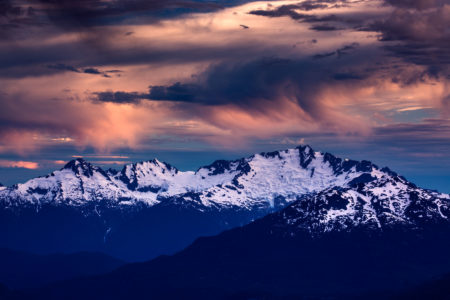 A passing storm lights up at sunset over Tantalus Mountian in the Coastal Mountains near Vancouver, British Columbia Canada. Whistler Photographer